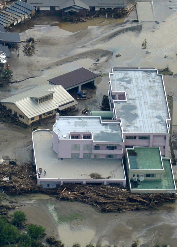 A flooded nursing home, center left, is seen in Iwaizumi town, Iwate prefecture, northern Japan, Wednesday, Aug. 31, 2016, after Typhoon Lionrock dumped heavy rains. Nine bodies were found Wednesday at the nursing home, police said. (Kyodo News via AP)